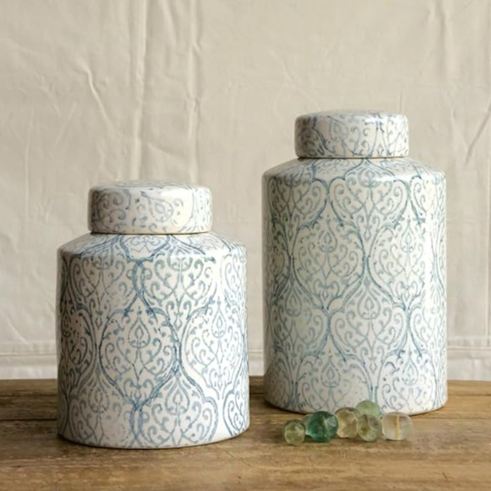 Two ceramic jars with decorative patterns on a wooden surface.